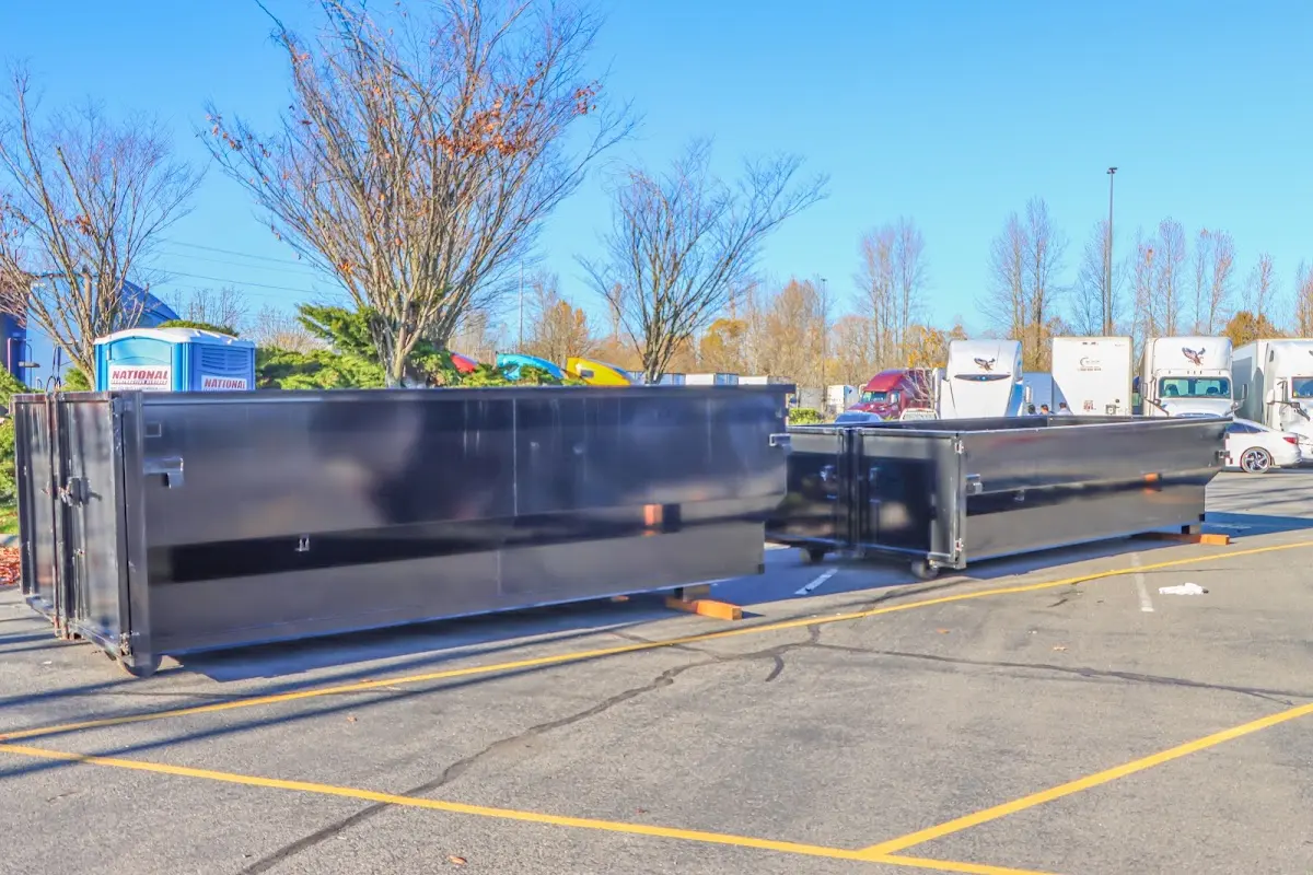 Professional dumpster rental service with roll-off container on residential driveway in East Point
